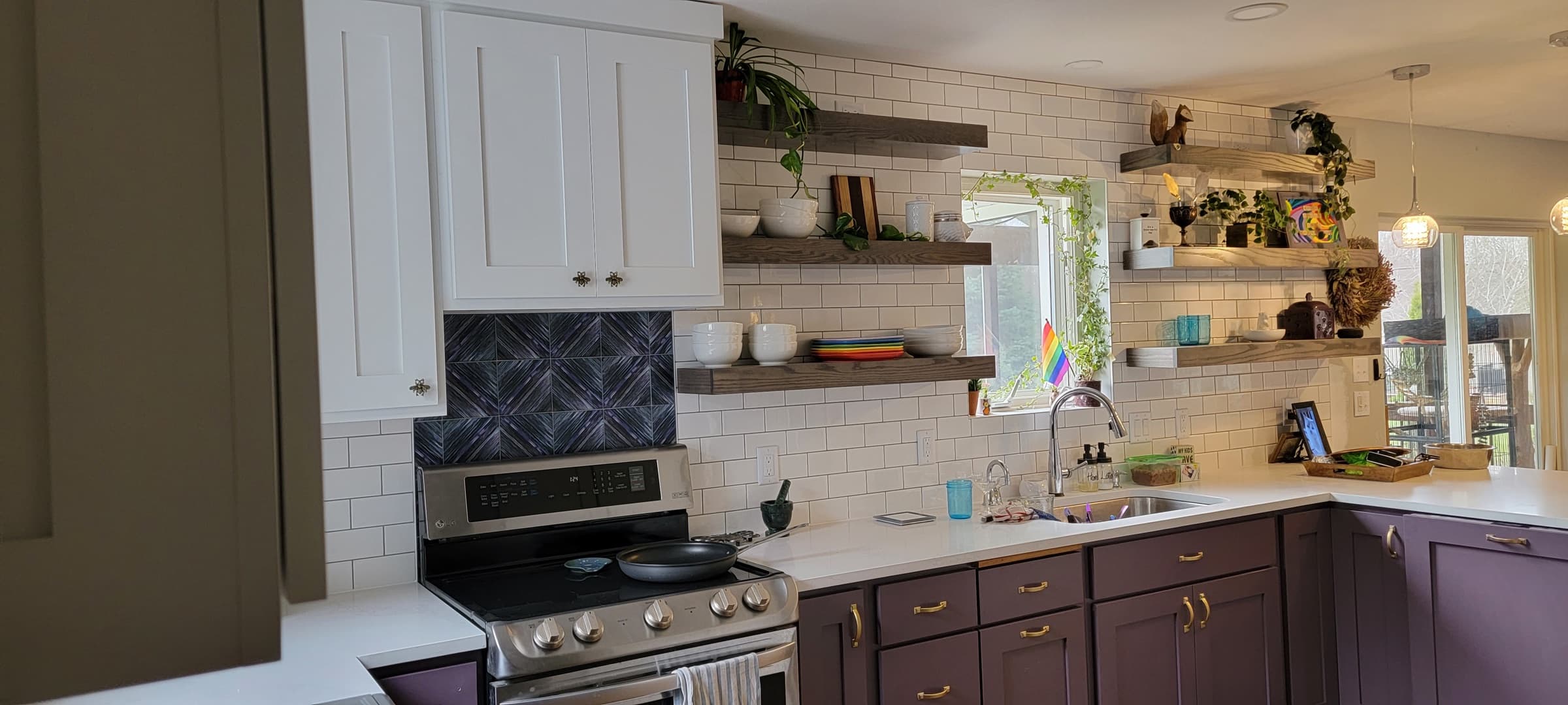 Kitchen detail showing subway tile backsplash, floating wood shelves, and painted cabinetry