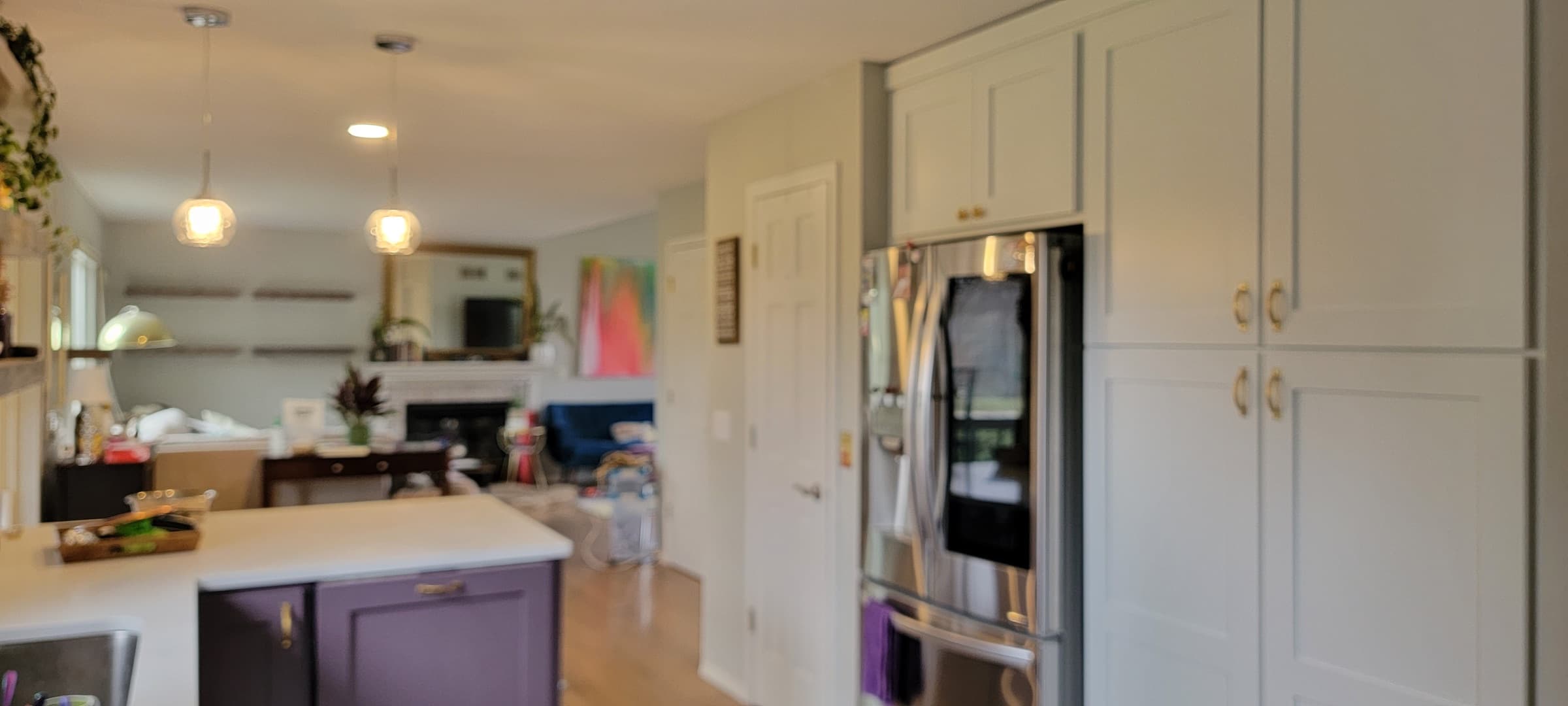 Remodeled kitchen with two-tone cabinetry, stainless refrigerator, and open sightline to the living room